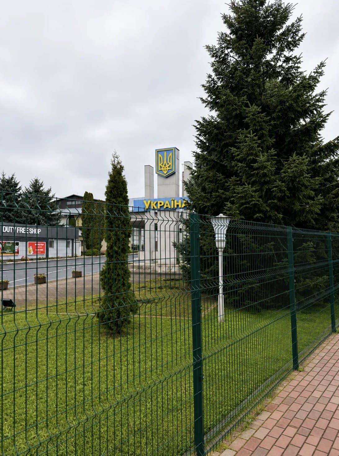 The Ukraine border sign by day behind a green fence